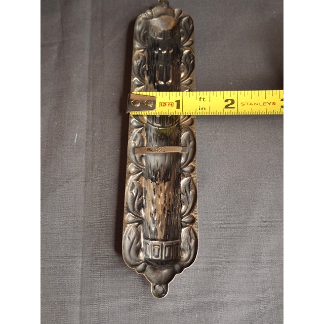 This is an exceptional .925 sterling silver repoussé mezuzah case featuring a highly detailed, multi-textured relief...