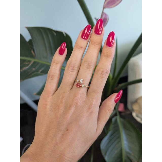 A 1.02-carat padparadscha sapphire glows in a warm blend of pink and orange at the centre of this solid 14K yellow gold...