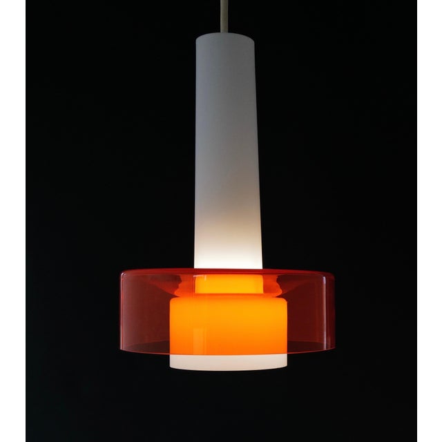 Striking pair of mid-century pendant lights featuring elongated white opaline glass cones paired with bold, transparent...