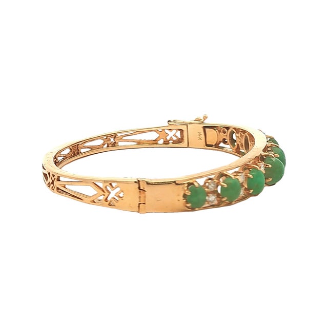 A stunning 14k gold bracelet featuring cabochon-cut emeralds. The vibrant green stones are complemented by round-cut white...