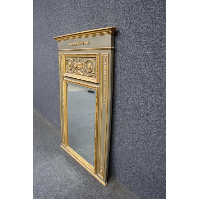 The painted wood frame features a soft gray finish with hand-applied gilt detailing. Carved laurel swags, an urn motif,...