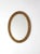 A charming mid-century oval gilt mirror featuring an ornate floral relief frame with elegant French Revival influence. The...