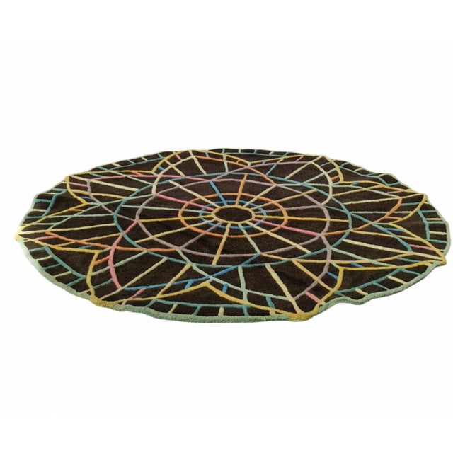 Round rug with an intricate and colorful pattern. Made using a hand-tufted technique in which each individual thread is...