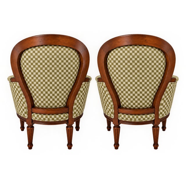 Elegant pair of Louis XVI-style walnut armchairs featuring curved backs, tapered fluted legs, and tailored green patterned...