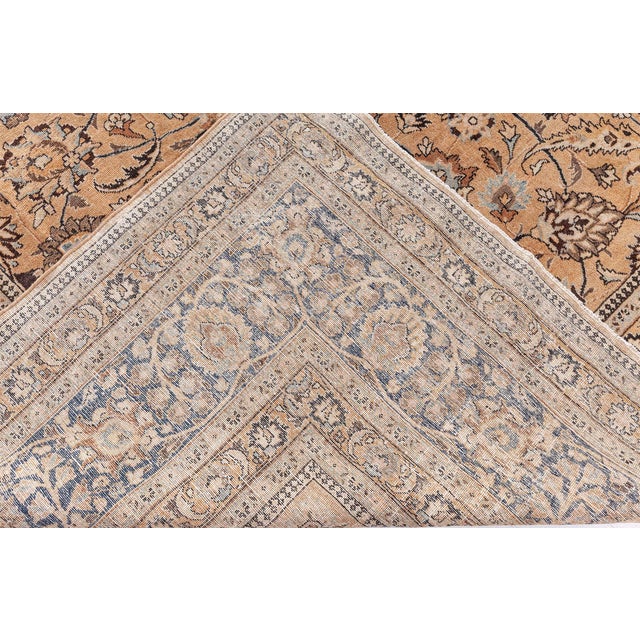 An early 20th century Persian Antique Tabriz rug, the peach field with an allofver lattice of enlarged stylized palmettes...