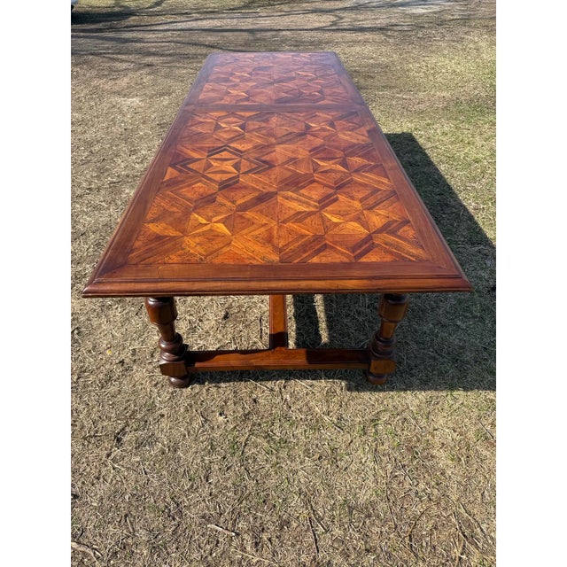 French table featuring an intricate parquetry top made of richly grained hardwoods arranged in a geometric star pattern....