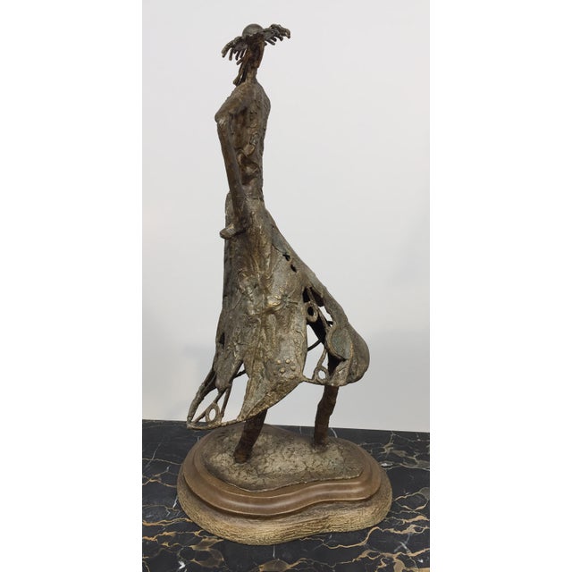 This one-of-a-kind sculpture is in an array of mixed media. The wooden base seems to be covered partially in the same type...