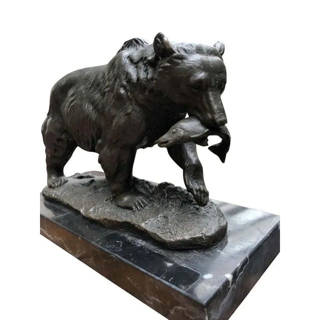 A gorgeous bronze casting of an american grizzly bear, 20th century. The bear is depicted with a salmon in its mouth. The...