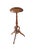 An antique Victorian mahogany torchère pedestal stand features a small, circular flat tabletop bordered by a simple...