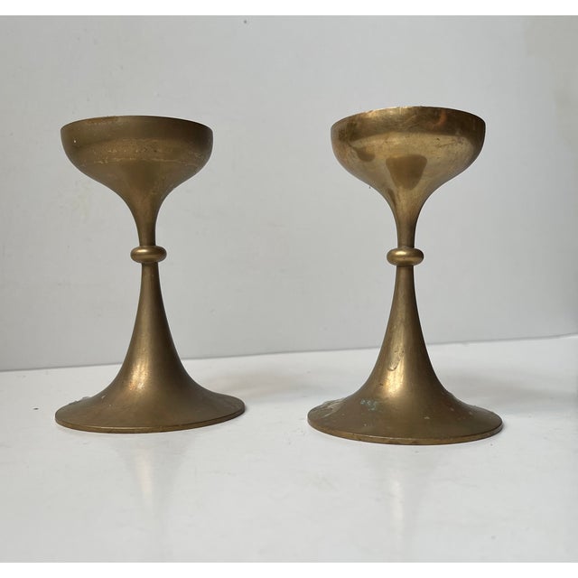 A pair of trumpet shaped brass candlesticks designed and manufactured in Scandinavia during the 1960s. The candlesticks...