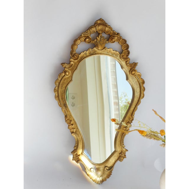 A vintage ornate French baroque style mirror from the 70's. The wall mirror has a beautiful frame with a floral carved...