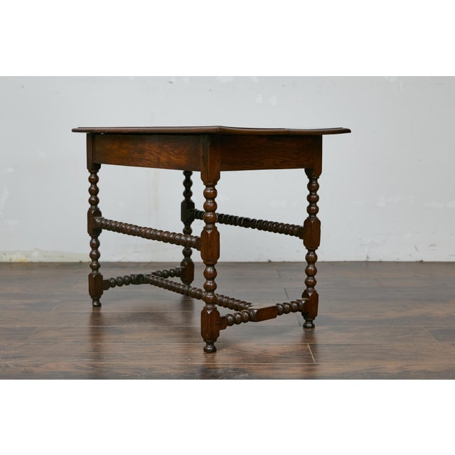 An English bobbin leg oak side table from the 19th century with single drawer and H-Form cross stretcher. This English...