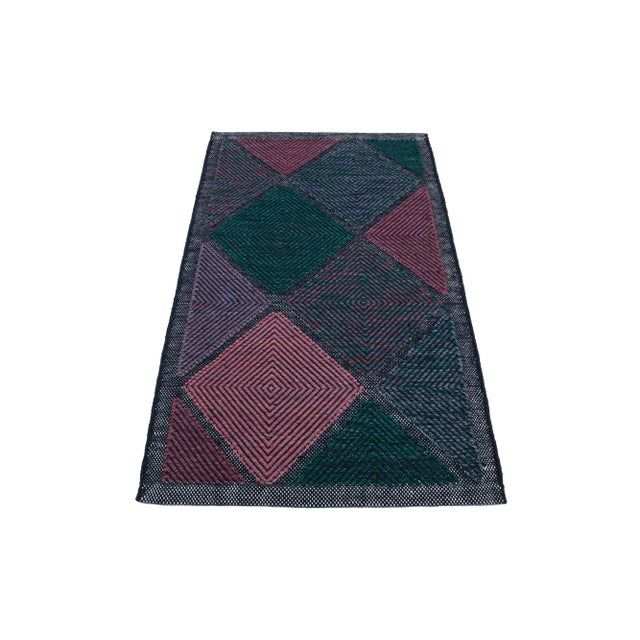 This flatweave rug showcases a contemporary Swedish design with a gray base. It's accented with green, purple, and pink...