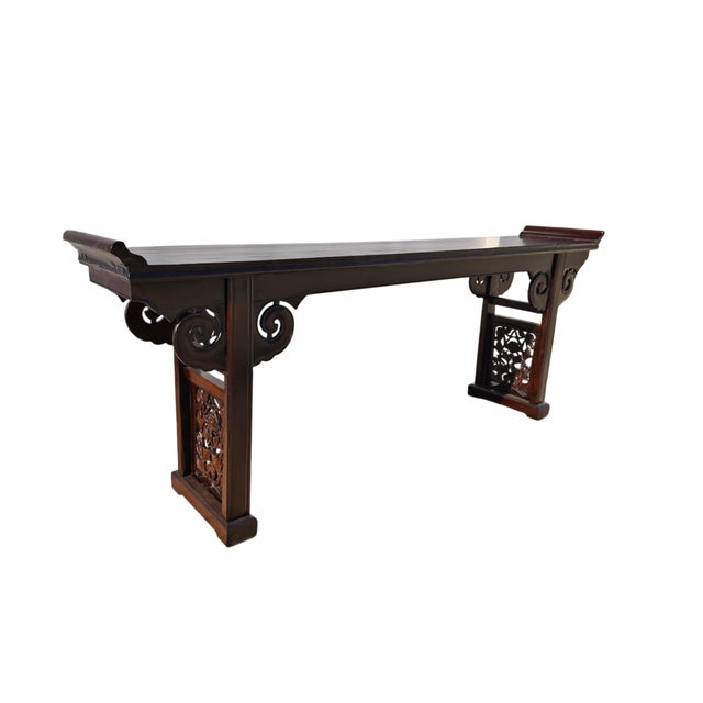 This antique altar table showcases an elegant, elongated silhouette with a rich, dark lacquer finish. The flush...