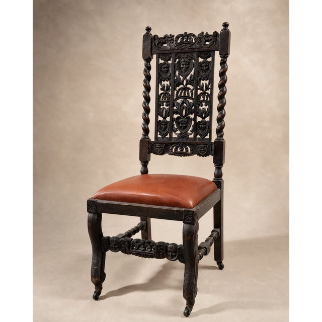 An impressive pair of antique Jacobean Revival carved oak hall chairs featuring elaborate openwork backs with heraldic...