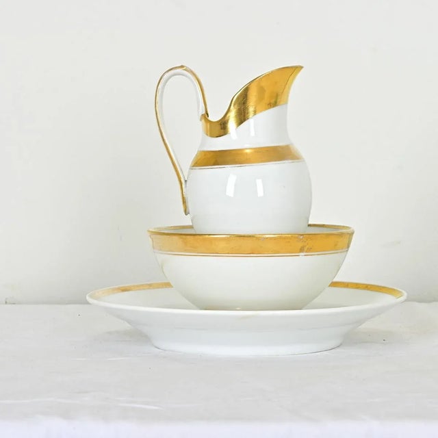 An elegant, three-piece set of old Paris porcelain in the style of Lebon-Halley with a pitcher, bowl, and deep plate in...