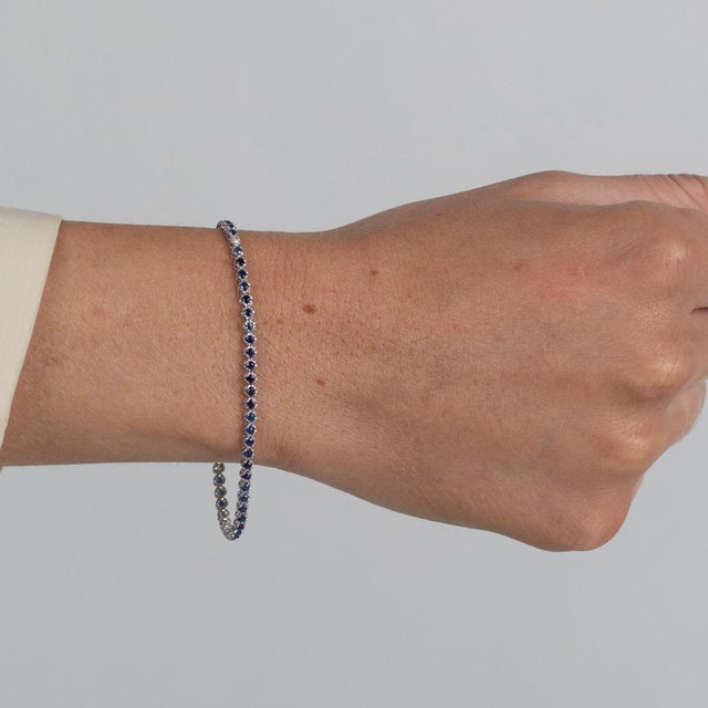 1.5 carat total weight natural blue sapphire tennis bracelet in 14K white gold. Item pictured in 7-inch length, adjustable...
