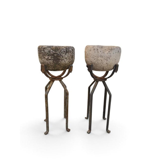 An attractive and highly decorative pair of 19th-century carved stone planters, each raised on an elegant hand-forged iron...