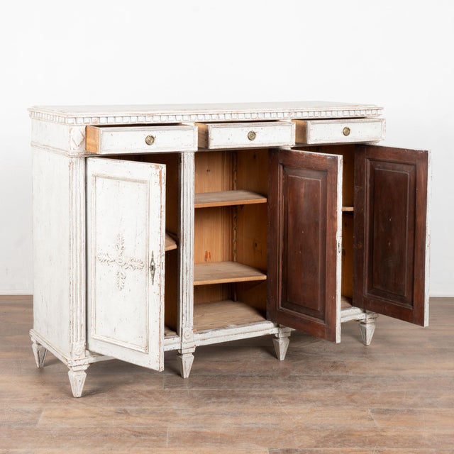 19th century Swedish Gustavian tall sideboard, crafted in pine. The cabinet has a newer layered antique white painted...