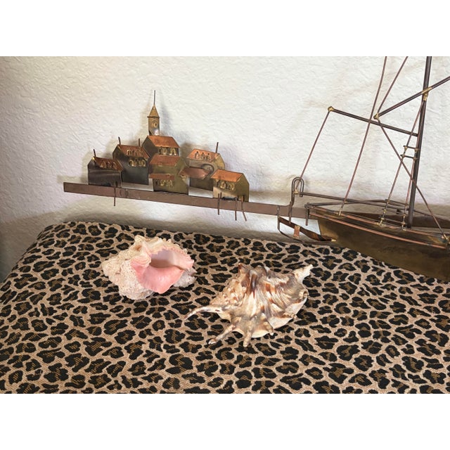 A striking Mid-Century Modern brass sculpture by Curtis Jere, featuring two stylized sailboats with tall, sweeping sails....