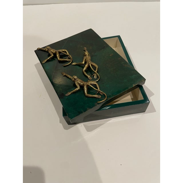 A decorative box made from green penshell inlay with a trio of brass monkeys as accent. It is handmade. Specks of brown...