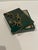 A decorative box made from green penshell inlay with a trio of brass monkeys as accent. It is handmade. Specks of brown...