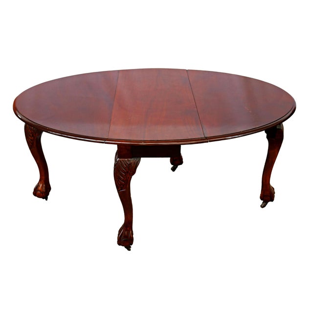 Folding mahogany dining table made in the mid-20th century. Round shape with foldable side wings. Hand-carved legs with...