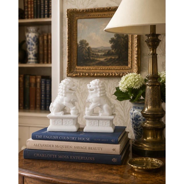 A charming pair of late 20th-century Chinese foo dog statues carved or cast in white stone, each modeled in the...