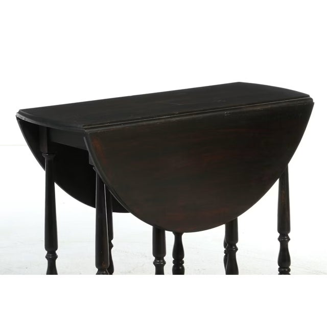 This antique William and Mary style gate-leg table commands attention with its dramatic silhouette and deep, dark painted...