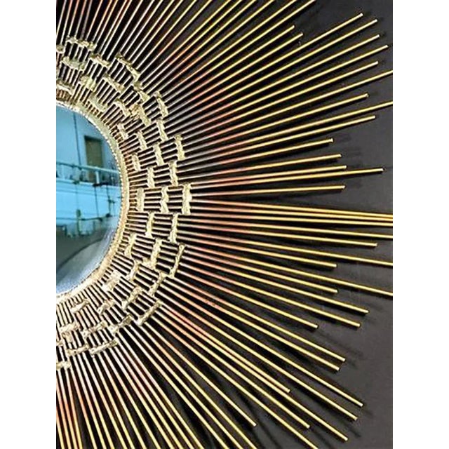 Gorgeous radiating spoke wall sculpture with round mirror centre in burnished brass toned metal. Mirror framed with...