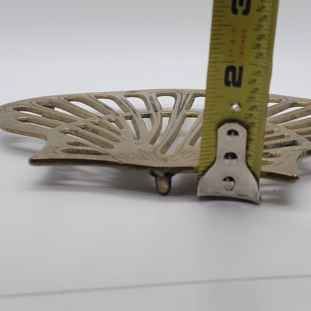 Vintage solid brass trivet featuring a classic scalloped seashell or fan design. This heavy-duty metal piece includes...