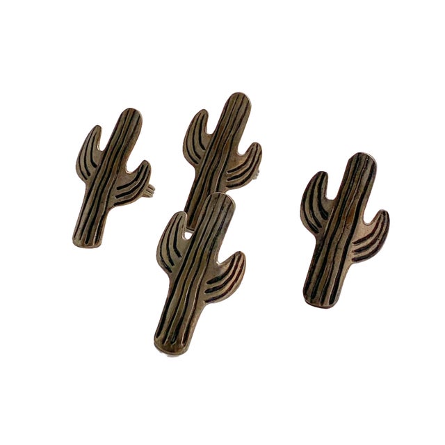 Set of four vintage napkin rings featuring stylized saguaro cactus silhouettes with engraved detailing and an aged silver-...