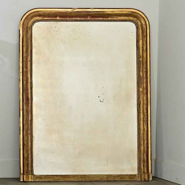 A lovely gilt mantel mirror from 19th century France, the tall proportions of the Louis Philippe style arch-top frame are...