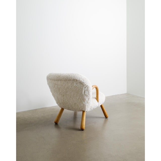 A rare and iconic danish mid century "clam chair" in natural stained beech wood and white sheepskin designed by arnold...
