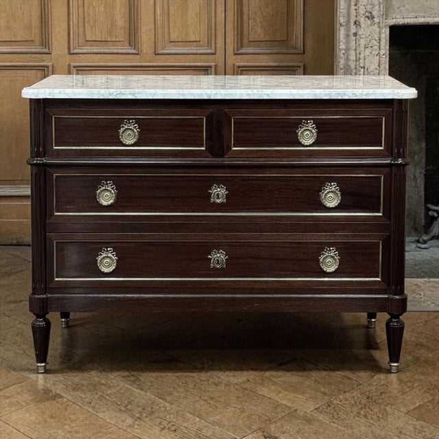 Elegant and finely composed, this French Louis XVI Mahogany Carrara Marble Top Commode pairs the richness of mahogany with...