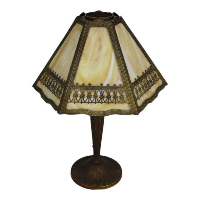 This antique Arts & Crafts table lamp, attributed to Bradley & Hubbard, features a distinctive six-panel slag glass shade....