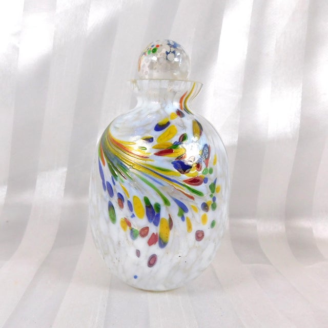 This is a white and multicolor metallic and iridescent art glass perfume bottle. The main bottle is clear and white and it...