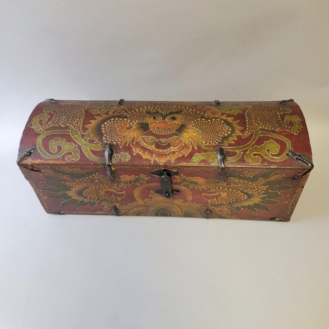 A striking mid-century Tibetan manuscript box, hand-decorated and richly adorned with a powerful dragon surrounded by...