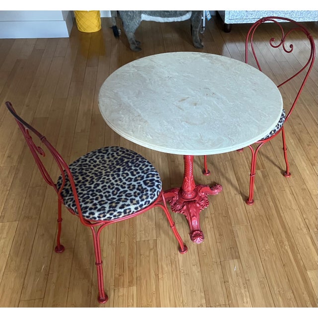 Marble table with cast iron base and two metal chairs with leopard seats. The table is 30" across and 27" high; the chairs...