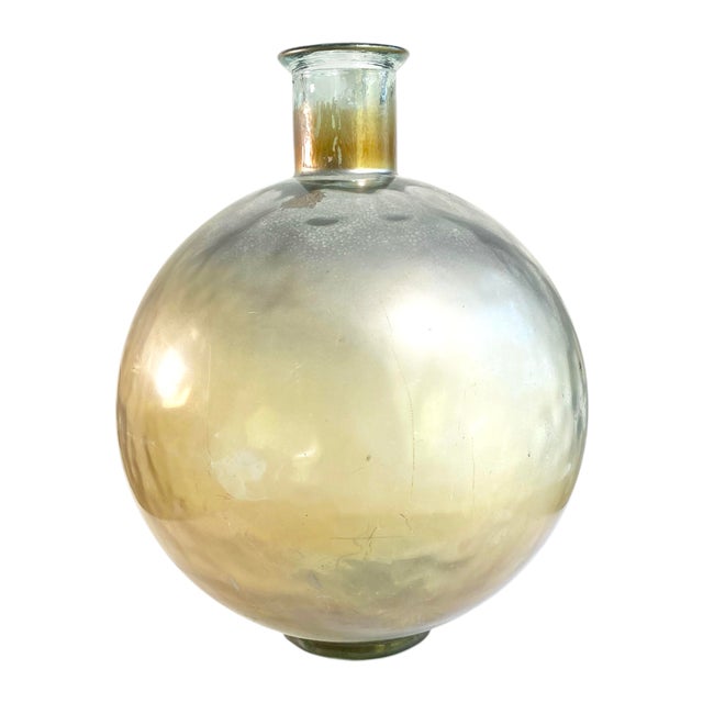 A large industrial glass globe on a stepped base with short flared neck and a metallic patina. Vintage.