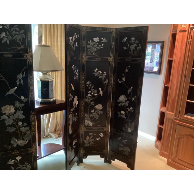 This Chinoiserie screen is black lacquered with Asian motifs including exotic birds, bamboo and flowering trees and...