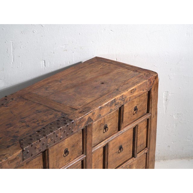 This antique multi-drawer cabinet in pine wood features a 15 drawer grid with ring-shaped hand-forged iron pulls and a...