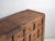 This antique multi-drawer cabinet in pine wood features a 15 drawer grid with ring-shaped hand-forged iron pulls and a...