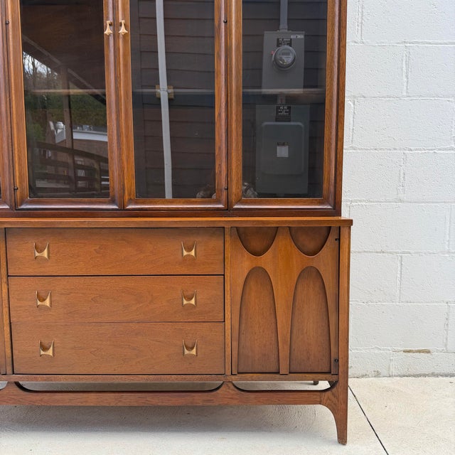 Two-piece mid-century “Brasilia” walnut hutch by Broyhill, combining sculptural detail with clean, functional storage. The...
