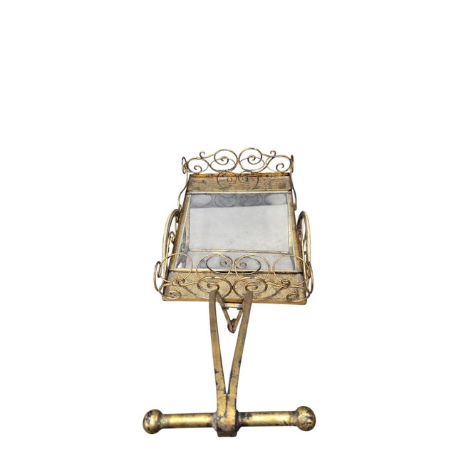 Hollywood Regency Gilt Iron Tea/Bar Cart with Glass Shelves and Scrollwork Wheels A striking Hollywood Regency tea or bar...