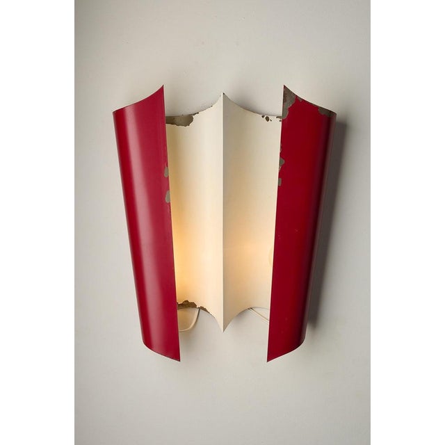Wall sconce designed by Bruno Gatta for Stilnovo in Italy during the 1950s. The fixture features a bent aluminum structure...
