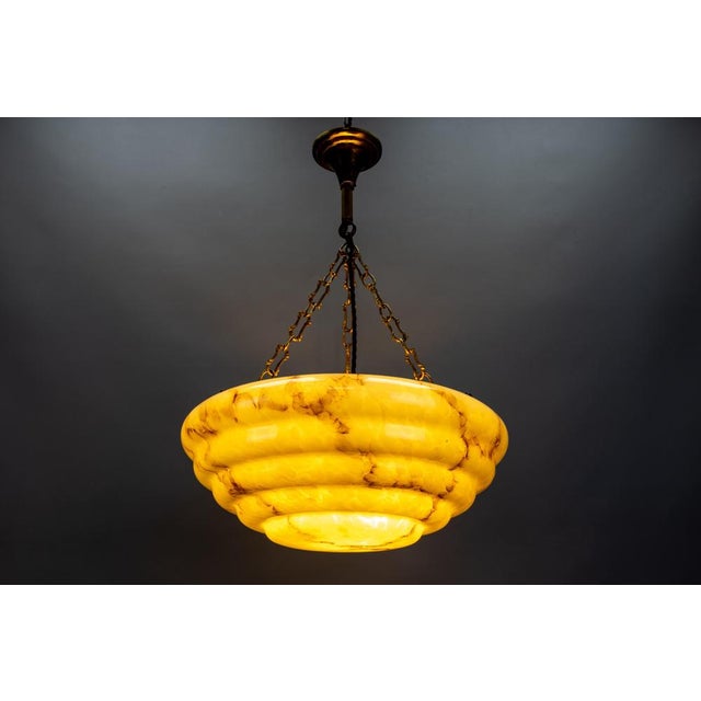 An Art Deco style marbled layered yellowish beige and brown glass and brass pendant light from the 1950s, Germany. This...