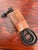 Corded desk telephone covered in stitched tan leather. The slim handset rests on a matching leather base. The keypad sits...