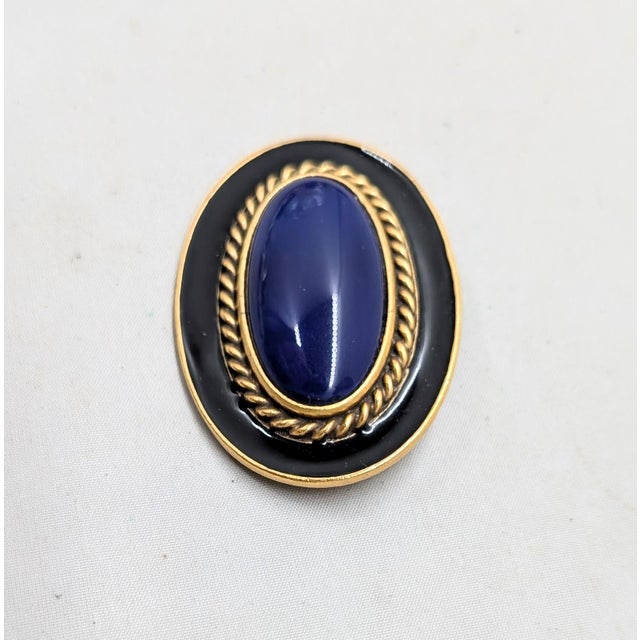 1980s oval goltone oval faux-lapis with textured goldtone rope design surround with black enamel on the outside brooch...