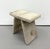 A sculptural stool fully upholstered in natural cream and taupe hair-on-hide, featuring a broad rectangular seat with a...